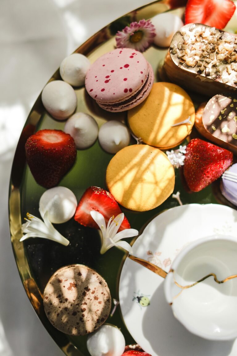 Close-up of colorful macarons and strawberries on a decorative plate.